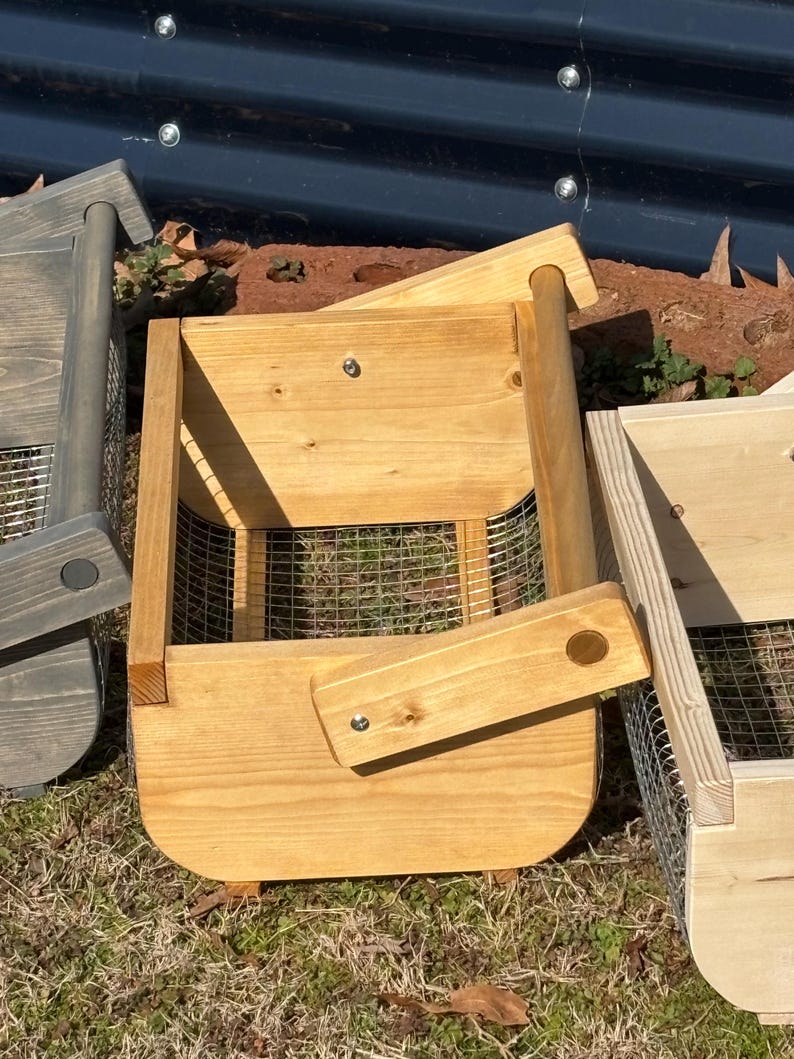 May include: Two wooden baskets with wire mesh bottoms and wooden handles. The baskets are made of natural wood and have a light brown stain. The baskets are sitting on a bed of brown grass.