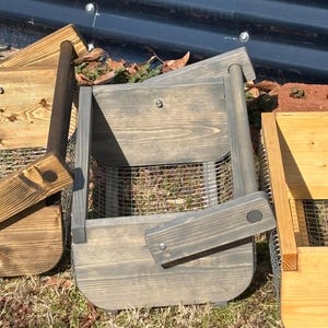 May include: Two wooden storage baskets with wire mesh bottoms. The basket on the left is brown and the basket on the right is gray.