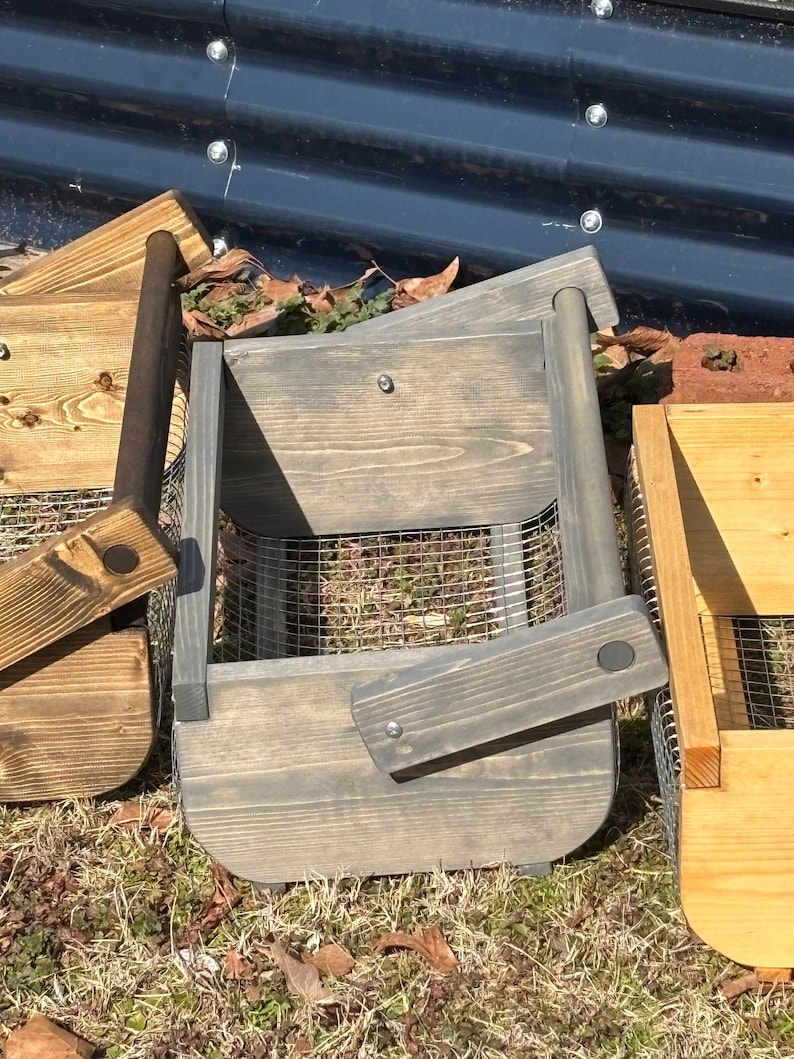 May include: Two wooden storage baskets with wire mesh bottoms. The basket on the left is brown and the basket on the right is gray.