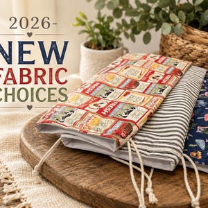 May include: Three fabric pouches with different patterns rest on a wooden cutting board. One features a red and cream vintage food label design, another has black and white stripes, and the third has a blue floral pattern. The text "2026 - NEW FABRIC CHOICES" is displayed.