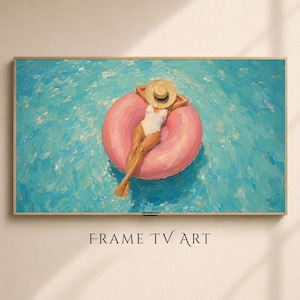 May include: A rectangular wall art piece in a light wood frame displaying an oil painting of a person in a white swimsuit and straw hat floating on a large pink circular pool float in bright blue water. The text FRAME TV ART is below the image.