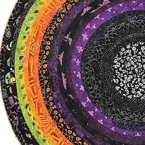 May include: Circular Halloween-themed quilt with concentric rings of fabric in a rainbow of colors. The quilt features patterns of bats, spiders, skulls, and other spooky motifs. The design is a vibrant and festive decoration for the Halloween season.