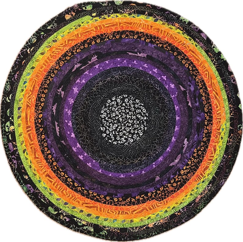 May include: A circular Halloween-themed rug with concentric rings of color. The rug features black, purple, orange, and green bands, with patterns of bats, spiders, and skulls. The center has a white skull design.