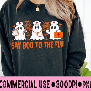 May include: Dark gray sweatshirt featuring three cartoon ghosts dressed as nurses, with medical tools and the text "SAY BOO TO THE FLU" in orange. The design includes bats and spiderwebs, perfect for Halloween or medical professionals.