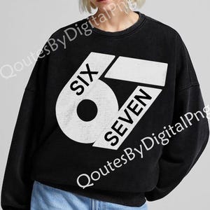 May include: Black crew neck sweatshirt with a large white graphic that reads "SIX SEVEN". The design is a bold, geometric arrangement of the numbers and words. The sweatshirt is a casual style.