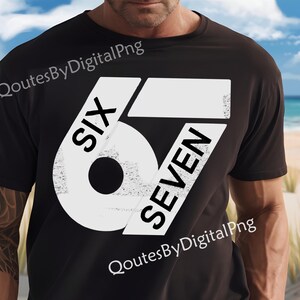 May include: Black t-shirt with a large white graphic design featuring the numbers "6" and "7" with the words "SIX" and "SEVEN" in a bold, sans-serif font. The shirt is worn by a person on a beach.