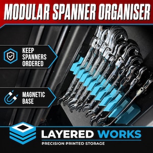 Puede incluir: Un organizador modular de llaves con base magnética, que presenta ranuras de color azul brillante que sostienen varias llaves de metal plateado. El texto dice MODULAR SPANNER ORGANISER, KEEP SPANNERS ORDERED, MAGNETIC BASE y LAYERED WORKS PRECISION PRINTED STORAGE.