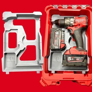Peut inclure: Une perceuse Milwaukee M18 Fuel rouge avec une batterie 5.0 Ah dans une mallette rouge dotée d'un insert en plastique gris sur mesure. Un insert gris vide identique est placé à gauche, tous deux portant le logo Printforge.