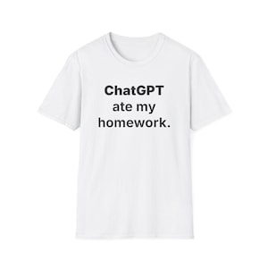 May include: White t-shirt with the text "ChatGPT ate my homework" in black, centered on the front. The shirt has a crew neck and short sleeves, suitable for casual wear.