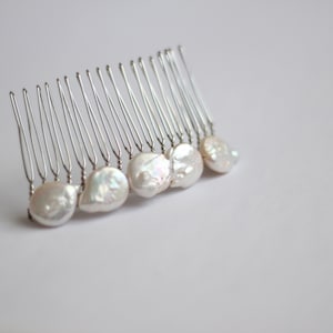 May include: A silver hair comb with a row of white pearl-like beads attached to the teeth.