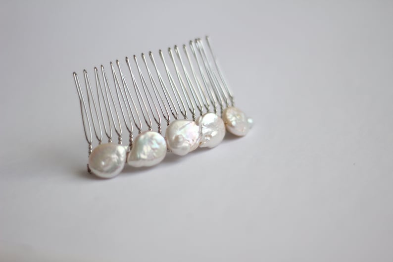 May include: A silver hair comb with a row of white pearl-like beads attached to the teeth.
