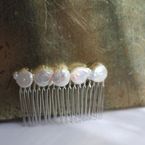 May include: A silver hair comb with five white pearl-like embellishments.