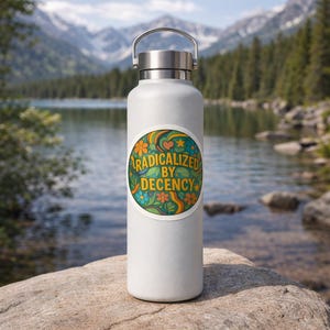 May include: A white insulated water bottle with a silver cap and handle. A circular sticker on the bottle features the text "RADICALIZED BY DECENCY" in a retro design with flowers, stars, and swirls in orange, green, and blue.