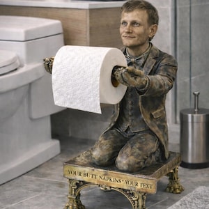 May include: A bronze-colored toilet paper holder in the shape of a kneeling figure in a suit, holding a roll of white toilet paper. The base of the holder has the text "YOUR BUTT NAPKINS YOUR TEXT". The holder is in a bathroom setting.