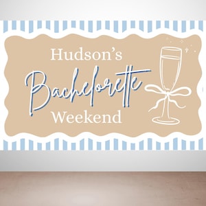 May include: A banner with the text "Hudson's Bachelorette Weekend" in a script font. The banner has a tan background with a white scalloped border and a light blue striped border. A champagne glass illustration is on the right.