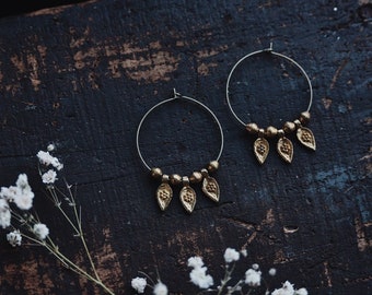 naira. a pair of brass bohemian floral teardrop hoop earrings.
