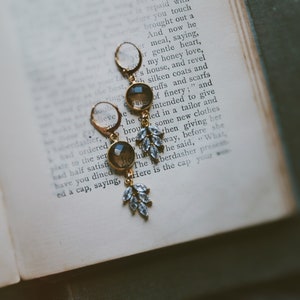 May include: A pair of gold earrings with a teardrop-shaped, clear glass stone and a dangling cluster of clear crystals.