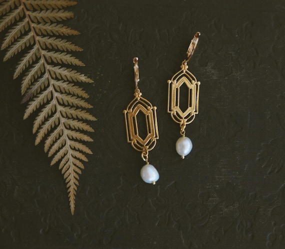 rococo. a pair of ornate gold brass and freshwater pearl earrings.