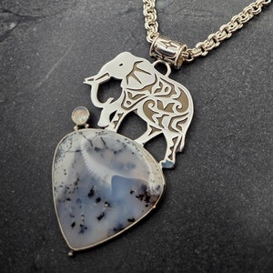 May include: A silver chain necklace with a pendant featuring a detailed elephant silhouette and a heart-shaped agate stone.