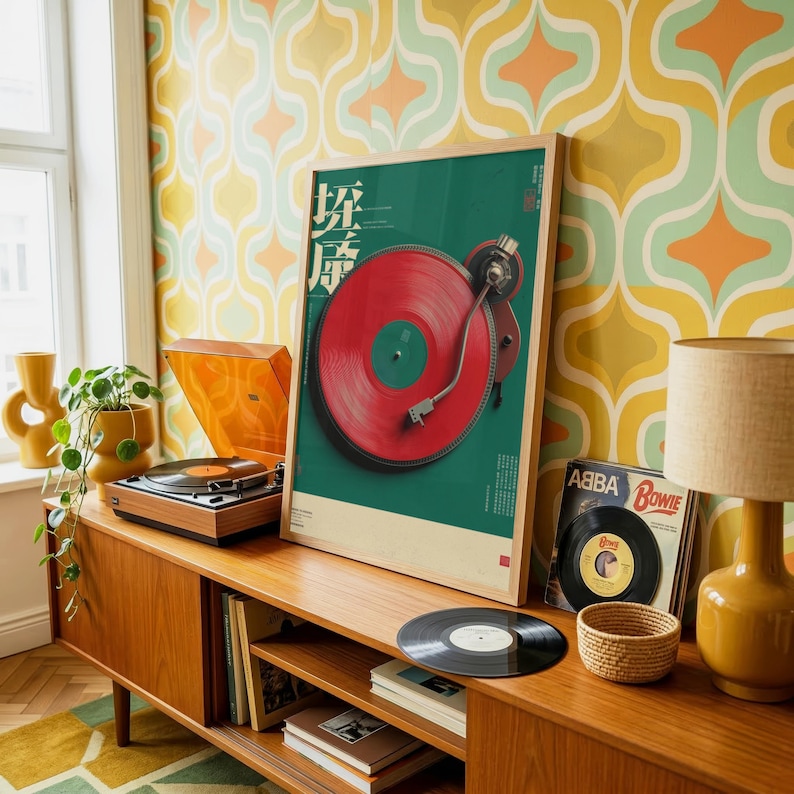 May include: A framed vertical poster featuring a graphic illustration of a red vinyl record on a turntable against a dark green background with Japanese text. The poster is displayed on a wooden sideboard next to a record player and an ABBA record.