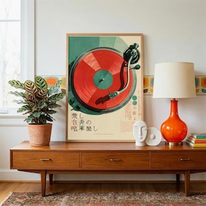 May include: A framed vertical poster featuring a graphic illustration of a turntable with a bright red vinyl record. The artwork includes Japanese text and a teal circular background. The poster is displayed on a wooden sideboard next to a plant.