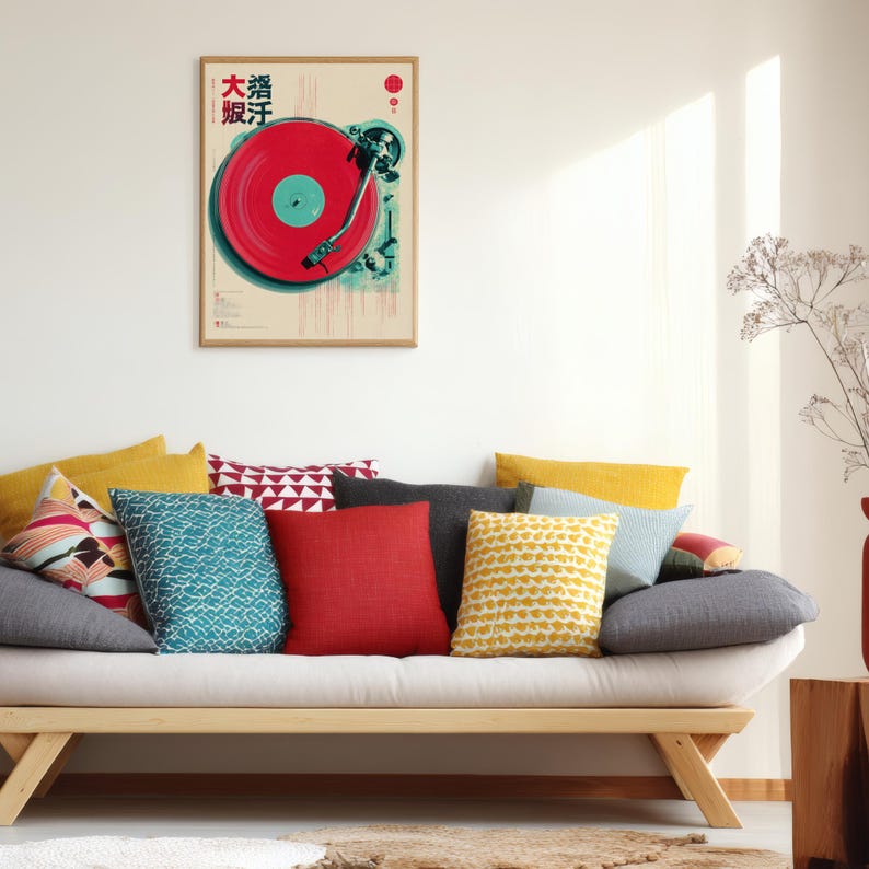 Op de afbeelding: Een ingelijste poster met een rode vinylplaat en Japanse tekst. De poster hangt boven een bank met kleurrijke kussens. De kamer heeft een minimalistisch design. De bank is ongeveer 200 cm lang.