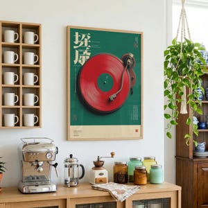 May include: A framed wall poster featuring a large red vinyl record on a dark green background with white Japanese text. The poster is displayed above a wooden counter with a silver espresso machine, a glass French press, and several jars.