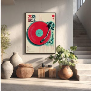 Op de afbeelding: Een ingelijste print met een vintage platenspeler met een rode plaat. Het kunstwerk heeft Japanse tekst en een minimalistisch ontwerp met een cr&egrave;mekleurige achtergrond en turquoise en rode accenten. De print staat in een modern interieur.
