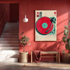 Op de afbeelding: Een ingelijste poster met een rode vinylplaat en Japanse tekst. Het kunstwerk hangt aan een rode muur, met een bank en een rieten mand op de voorgrond. Een trap en een hanglamp zijn ook zichtbaar.