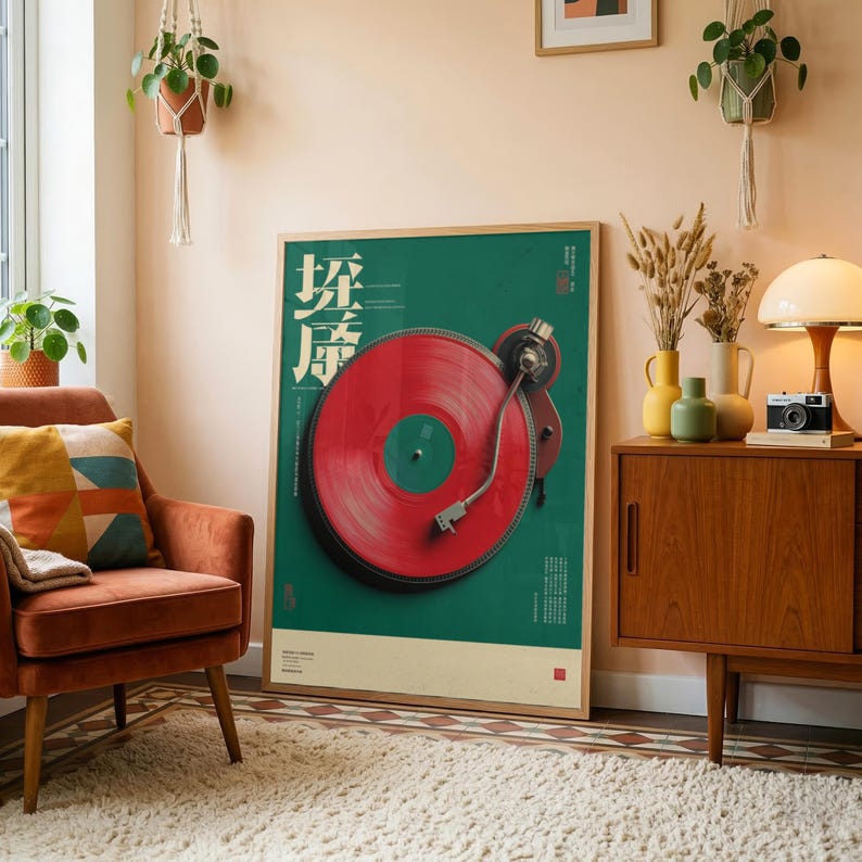 May include: A framed vertical poster featuring a vibrant red vinyl record on a dark turntable against a solid green background. The artwork includes stylized white Asian characters and small text elements. The poster is displayed in a light wood frame.