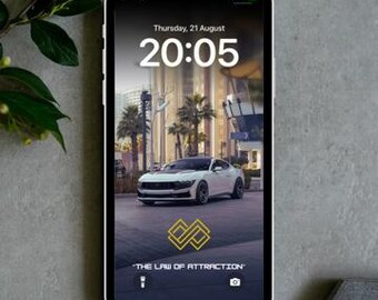 以下が含まれることがあります： 黒いスマートフォンは、ロック画面に20時05分と8月21日の日付を表示しています。画面には、ヤシの木のある通りに白い車と「THE LAW OF ATTRACTION」というテキストが表示されています。