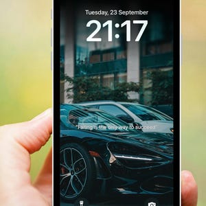 Puede incluir: Un teléfono inteligente muestra un fondo de pantalla de un coche deportivo negro con el texto "Failing is the only way to succeed". La pantalla muestra la fecha y hora: martes 23 de septiembre, 21:17.