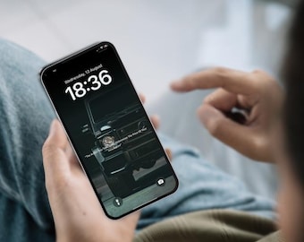 以下が含まれることがあります： 黒いスマートフォンは、黒い車両の暗い壁紙を表示しています。画面には18:36と8月13日水曜日の日付が表示されています。電話は誰かの手に持たれています。