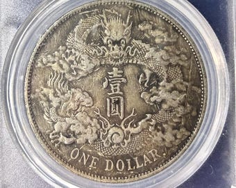 Könnte beinhalten: Eine Silbermünze in einem transparenten Kunststoffgehäuse. Die Münze zeigt ein detailliertes Drachendesign und chinesische Schriftzeichen. Der Halter enthält ein Etikett mit dem Text: "CHINA APPEARANCE MS 61 MECHANISM COIN".