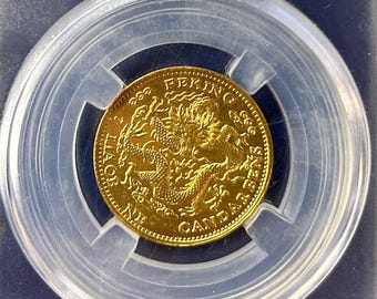 Könnte beinhalten: Eine Goldmünze in einem transparenten Kunststoffhalter. Die Münze zeigt ein detailliertes Drachendesign und Text. Der Halter enthält ein Etikett mit chinesischem und englischem Text sowie einen QR-Code. Die Münze hat einen Durchmesser von ca. 23,5 mm und wiegt 5,10 g.