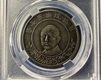 Könnte beinhalten: Eine chinesische Silbermünze, eingeschlossen in einem transparenten Kunststoffhalter. Die Münze zeigt ein Porträt und chinesische Schriftzeichen. Das Etikett des Halters enthält "NCAC AU 58 CHINA - YUNNAN" und "NUMISMATIC CULTURAL INNOVATION".