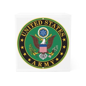 Könnte beinhalten: Ein weißer quadratischer Block mit dem Emblem der United States Army. Das kreisförmige Design hat einen grünen Hintergrund, einen goldenen Rand und die Worte "UNITED STATES ARMY" in Gold. In der Mitte befindet sich ein Adler mit Schild, Olivenzweig und Pfeilen.