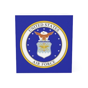 May include: A blue cube featuring the United States Air Force emblem. The emblem is a circular design with the words "United States Air Force" and a central crest with an eagle, stars, and a stylized sunburst.