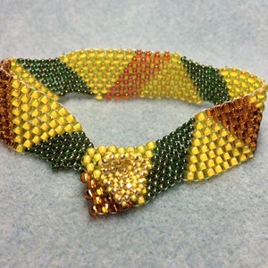 May include: A beaded bracelet with a woven pattern in shades of yellow, green, and brown.
