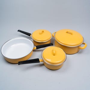 Peut inclure: Une tasse en céramique blanche avec une anse noire et le texte "But First, Coffee" en gras noir. La tasse est posée sur un fond flou, suggérant un cadre chaleureux.
