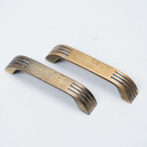 May include: A white ceramic mug with a black handle and the text "But First, Coffee" in a bold, black font. The mug is filled with a dark liquid, likely coffee, and sits on a light-colored surface.