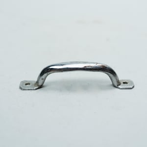 Peut inclure: Une poignée en métal chromé brillant, avec une poignée incurvée et deux plaques de montage rectangulaires avec des trous de vis. La poignée présente des signes d'usure et de décoloration.