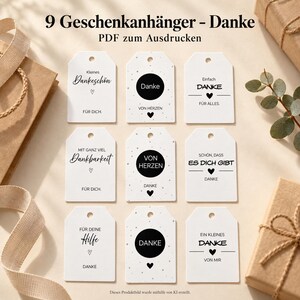 Op de afbeelding: Negen witte rechthoekige cadeaulabels met afgeronde bovenhoeken en een gat om op te hangen. Elk label bevat zwarte tekst en hartpictogrammen met verschillende Duitse zinnen die dankbaarheid uitdrukken, zoals Danke, Von Herzen en Für Dich, in een raster.