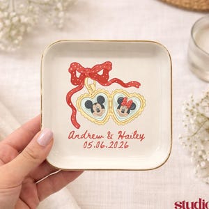 May include: A white ceramic mug with a black handle and the text "But First, Coffee" in a bold, black font. The mug is set against a blurred background, suggesting a cozy setting.