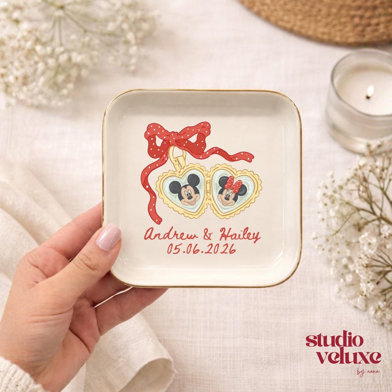 May include: A white ceramic mug with a black handle and the text "But First, Coffee" in a bold, black font. The mug is set against a blurred background, suggesting a cozy setting.