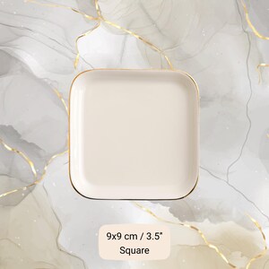 May include: A square, off-white ceramic plate with a gold rim. The plate measures 3.5 inches on each side. The text "Square" is below the measurement.