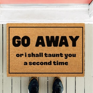 May include: A rectangular doormat made of natural coir fiber. The mat features the words "GO AWAY" in bold black letters, followed by "or i shall taunt you a second time" in a smaller font.