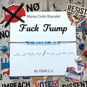 May include: A black string bracelet with blue and silver beads spelling out a message in Morse code. The words "Fuck Trump" are written above the bracelet. The image includes political protest stickers and a red "MAGA" hat with a red X.