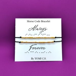 May include: Two Morse code bracelets with gold beads on black string, displayed on a white card against a purple background. The card reads "Always" and "Forever" in script, with the Morse code translation below each word.