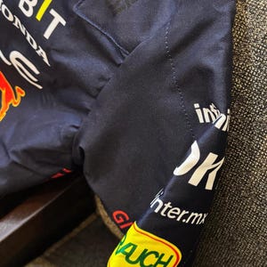 May include: Navy blue jacket with sponsor logos including "RAUCH", "BYBIT", and "HONDA". The jacket features red and white accents, and the "Castore" logo. The sleeve displays "inter.mx" and "Hard Rock" text.